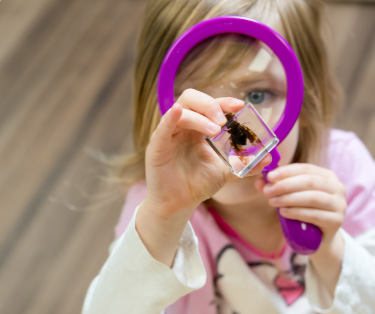 girl looking through pink magnifying glass